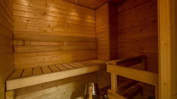 Uma sauna de madeira com bancos e um balde de metal.