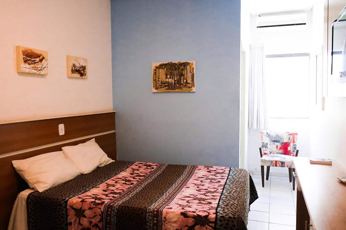 Un dormitorio con cama, escritorio y silla. Hay tres cuadros en la pared.