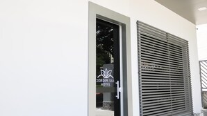 Una entrada de hotel moderna con puerta de cristal y persiana metálica.