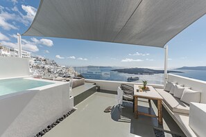 A rooftop terrace with a pool, seating area, and a view of the sea and distant islands. - Thera Villas (Santorini)