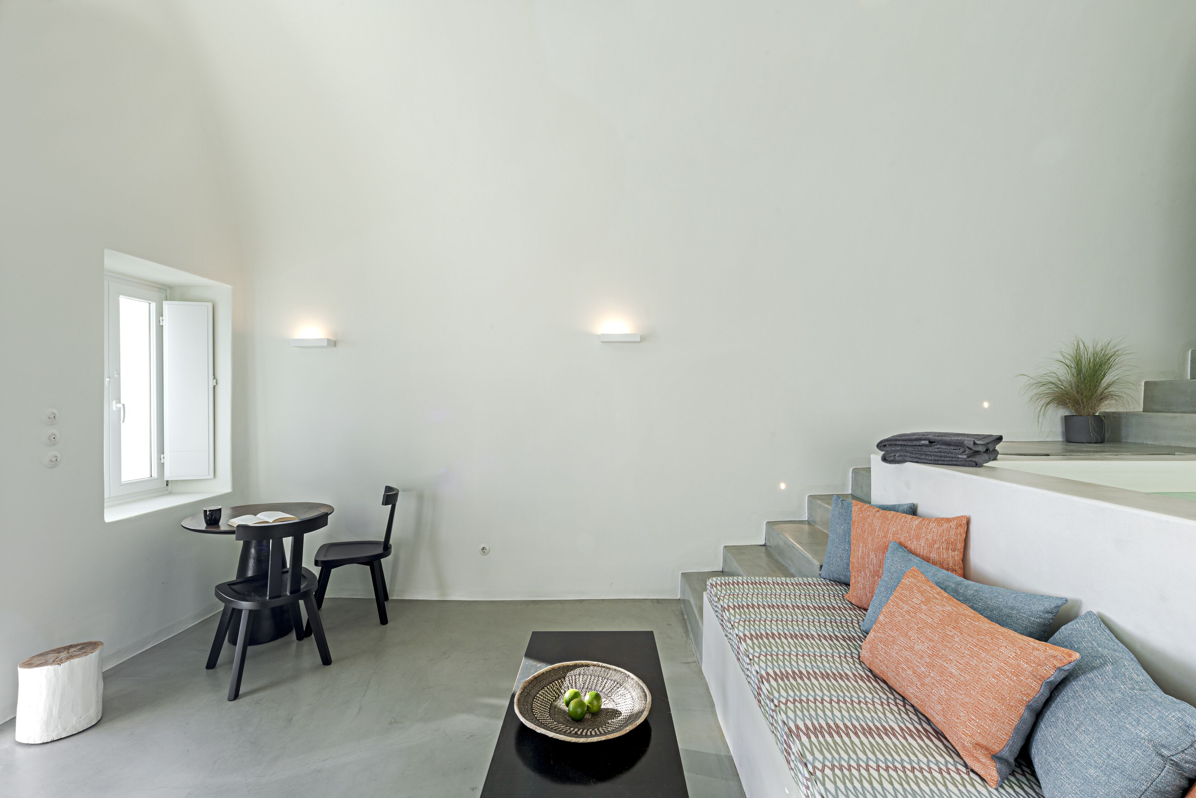 A modern living room with a sofa, a dining table with chairs, and a staircase leading to an upper level.