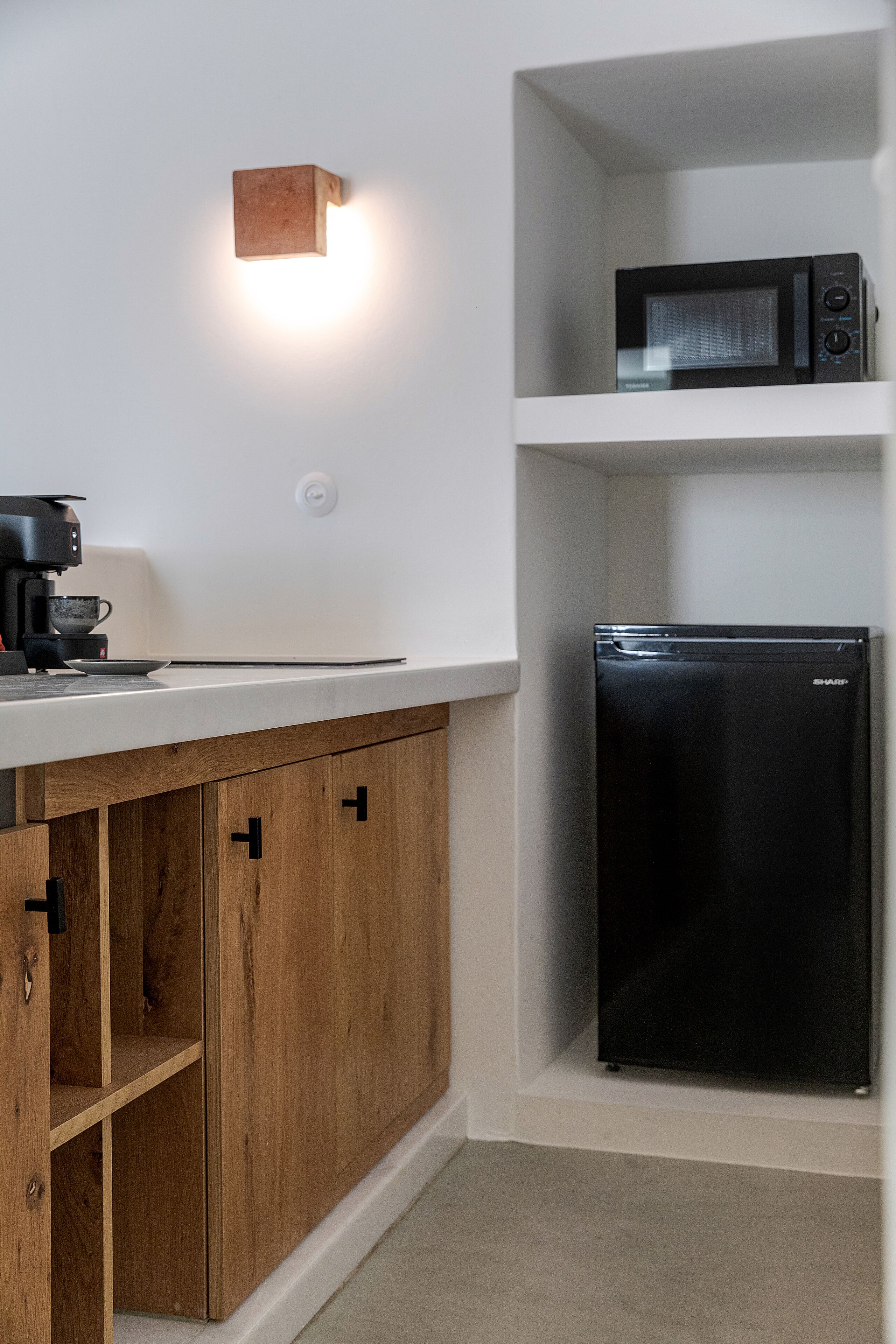 Una cocina equipada con cafetera, microondas y refrigerador.