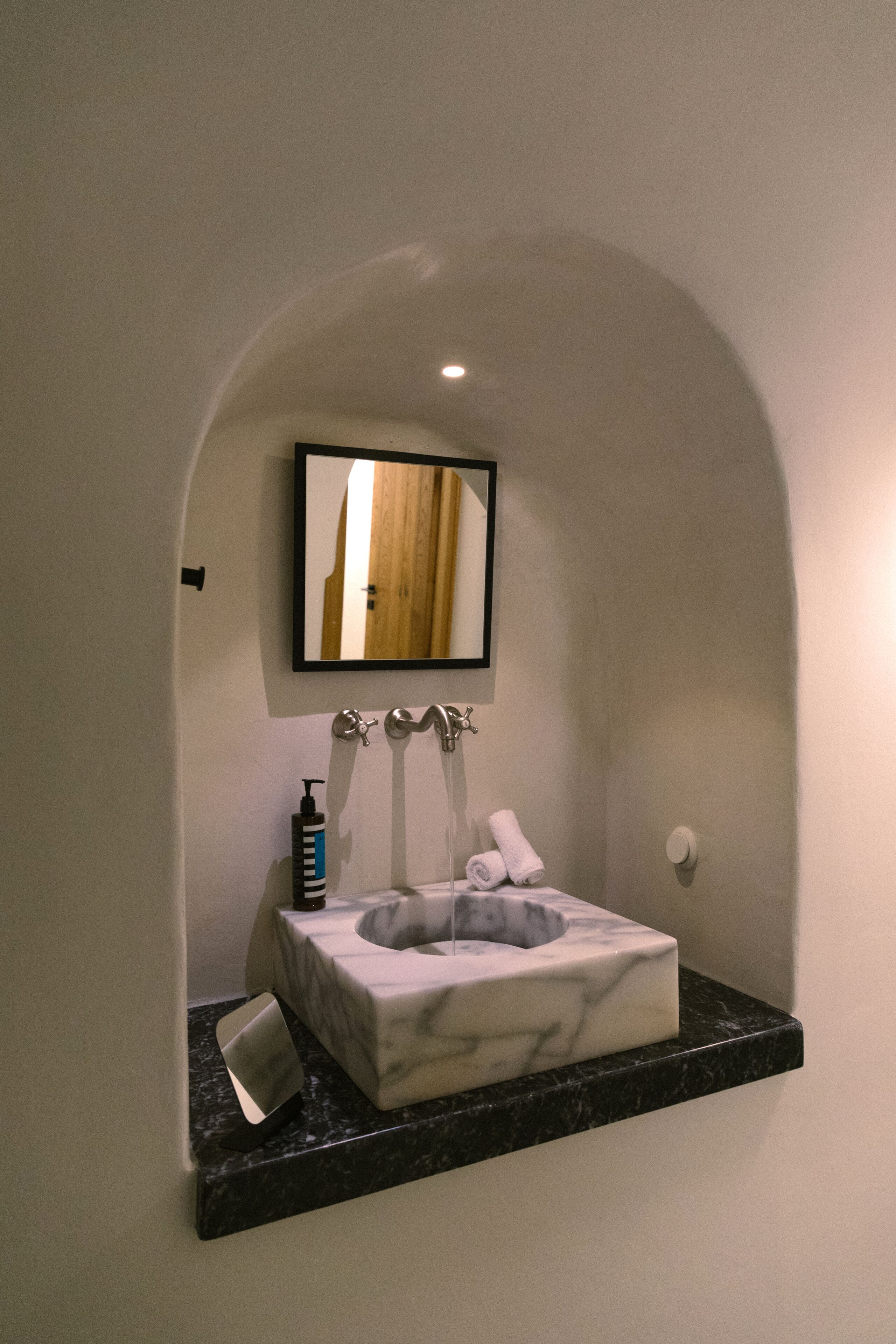 A bathroom with a marble sink, a mirror, and a towel rack.