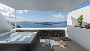 A balcony with a hot tub, a cactus, and a view of the sea and islands. - Thera Villas (Santorini)