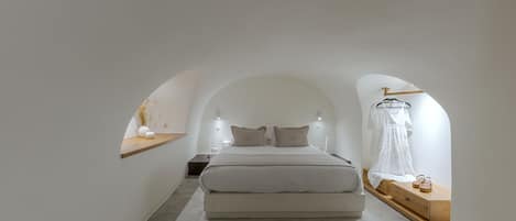 A minimalist bedroom with a large bed, bedside tables, and a hanging garment.
