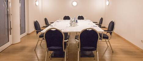 A conference room with a white table, six chairs, and a modern chandelier.