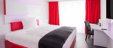 Una habitación de hotel moderna con una cama grande, un escritorio y una silla.