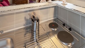 A kitchen with a modern stove, a sink, and a window with a curtain. - O'Lodge By Arvor Hotel (Dinan)