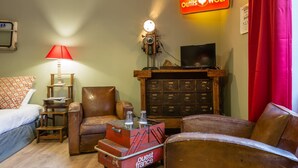 A cozy hotel room with a bed, a red lamp, a vintage television, and a wooden cabinet with drawers. - O'Lodge By Arvor Hotel (Dinan)