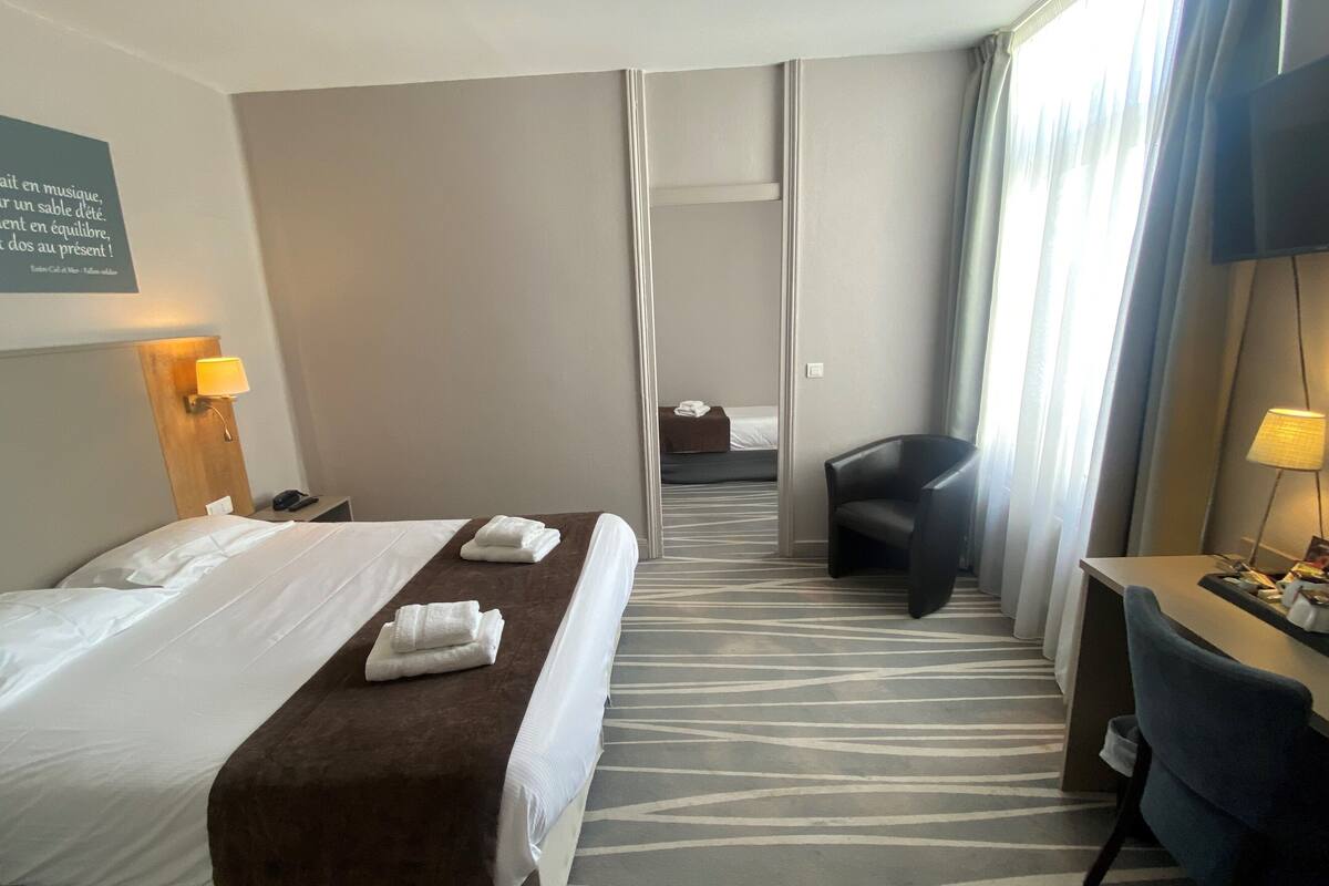 Ein Hotelzimmer mit Bett, Schreibtisch, Stuhl und einem Badezimmer im Hintergrund.