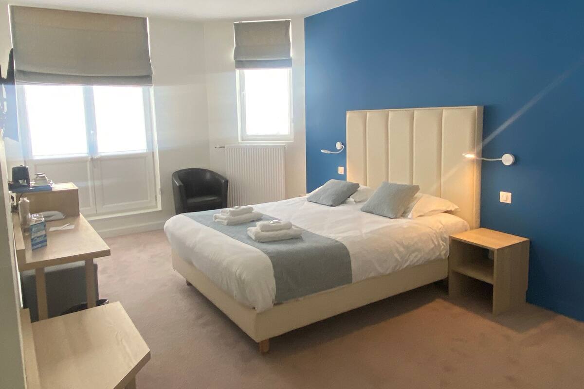 Ein modernes Schlafzimmer mit einem großen Bett, Nachttischen, einem Schreibtisch und einem Stuhl.