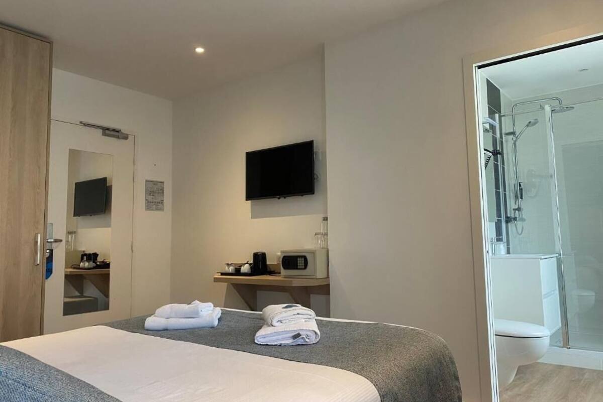 Ein Hotelzimmer mit einem Bett, einem Fernseher, einem Schreibtisch mit Mikrowelle und einem Duschbereich.