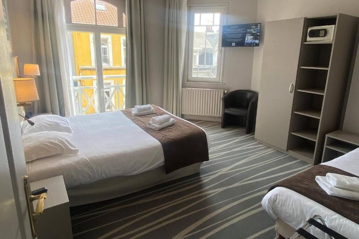 Ein Hotelzimmer mit einem Bett, einem Schreibtisch, einem Stuhl, einem Fernseher und einem Kleiderschrank.