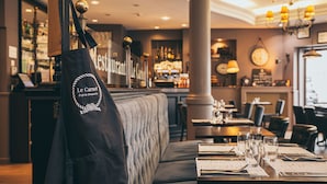A restaurant interior with a bar area, seating, and a menu stand. - Hôtel Villa Des 2 Caps (Wimereux)