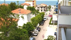 A street view with buildings, parked cars, and a speed limit sign. - Hotel Villa Lina (Riccione)
