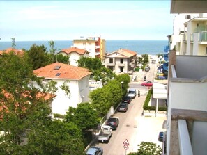 Vista da rua com edifícios, carros estacionados e uma placa de limite de velocidade.