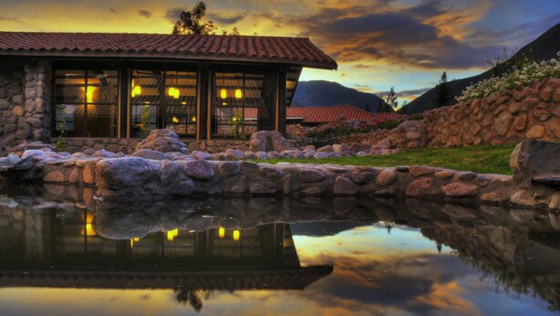 A stone building with large windows and a reflection in the water.