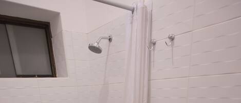 A bathroom with a shower, toilet, and a towel rack.