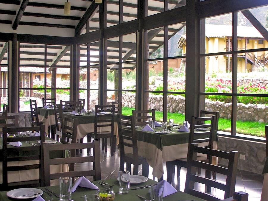 A restaurant with tables set for dining, large windows, and a view of the outdoors.