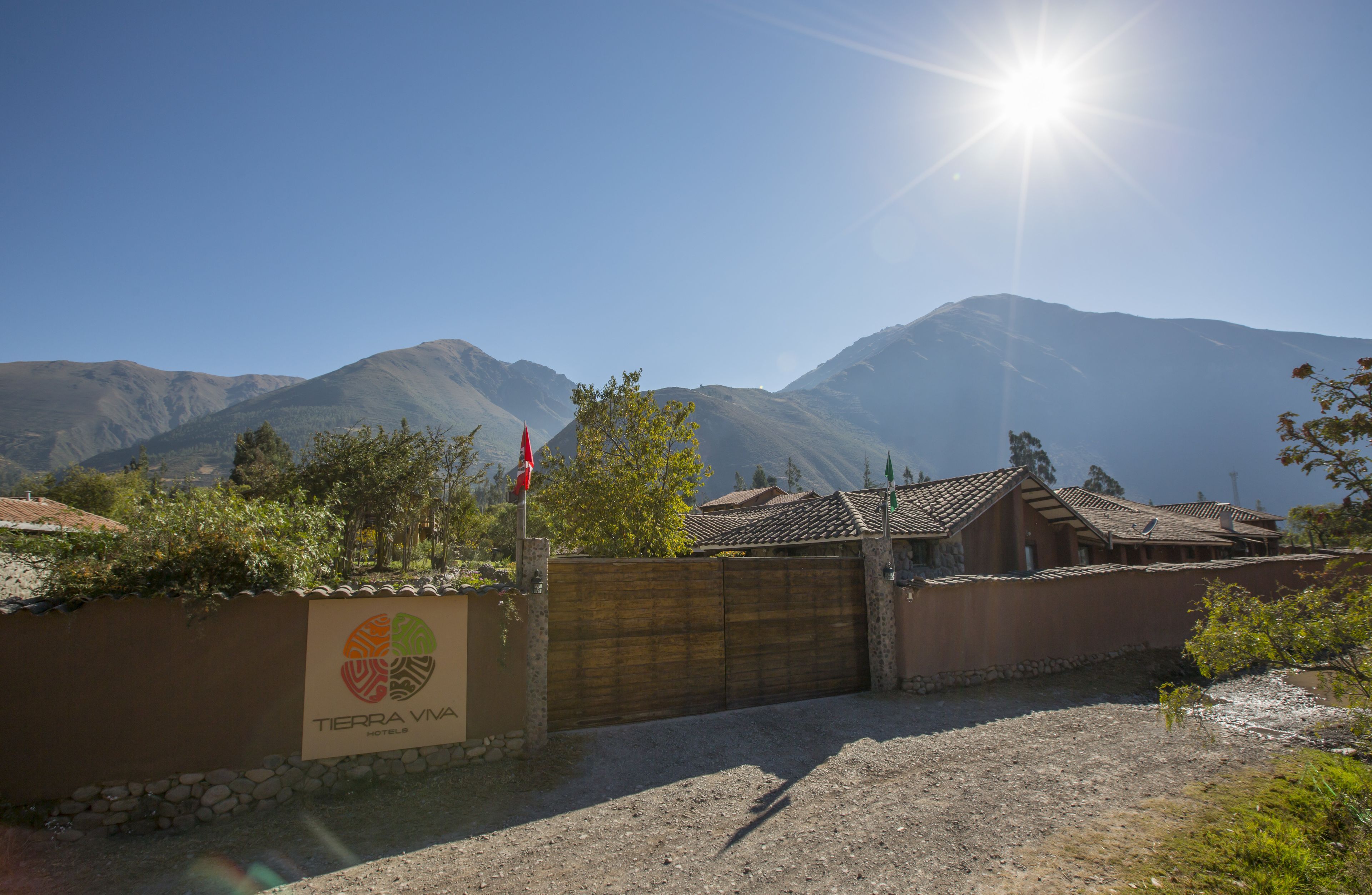 A hotel entrance with a sign reading "TIERRA VIVA HOTEL," a wooden gate, and a mountainous backdrop.