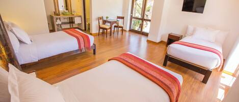 Habitación de hotel con dos camas, baño, zona de comedor y televisión.