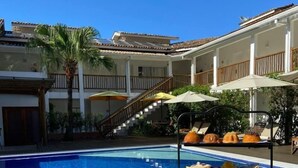 Zona de comedor junto a la piscina, con una mesa de buffet, una piscina y una escalera que lleva a un nivel superior.