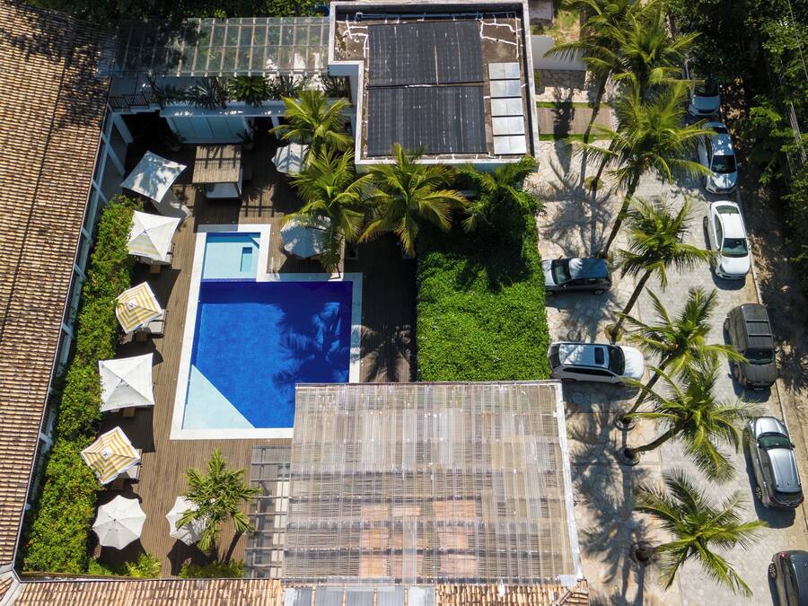 Vista aérea de una propiedad residencial con piscina, paneles solares y un estacionamiento con coches.