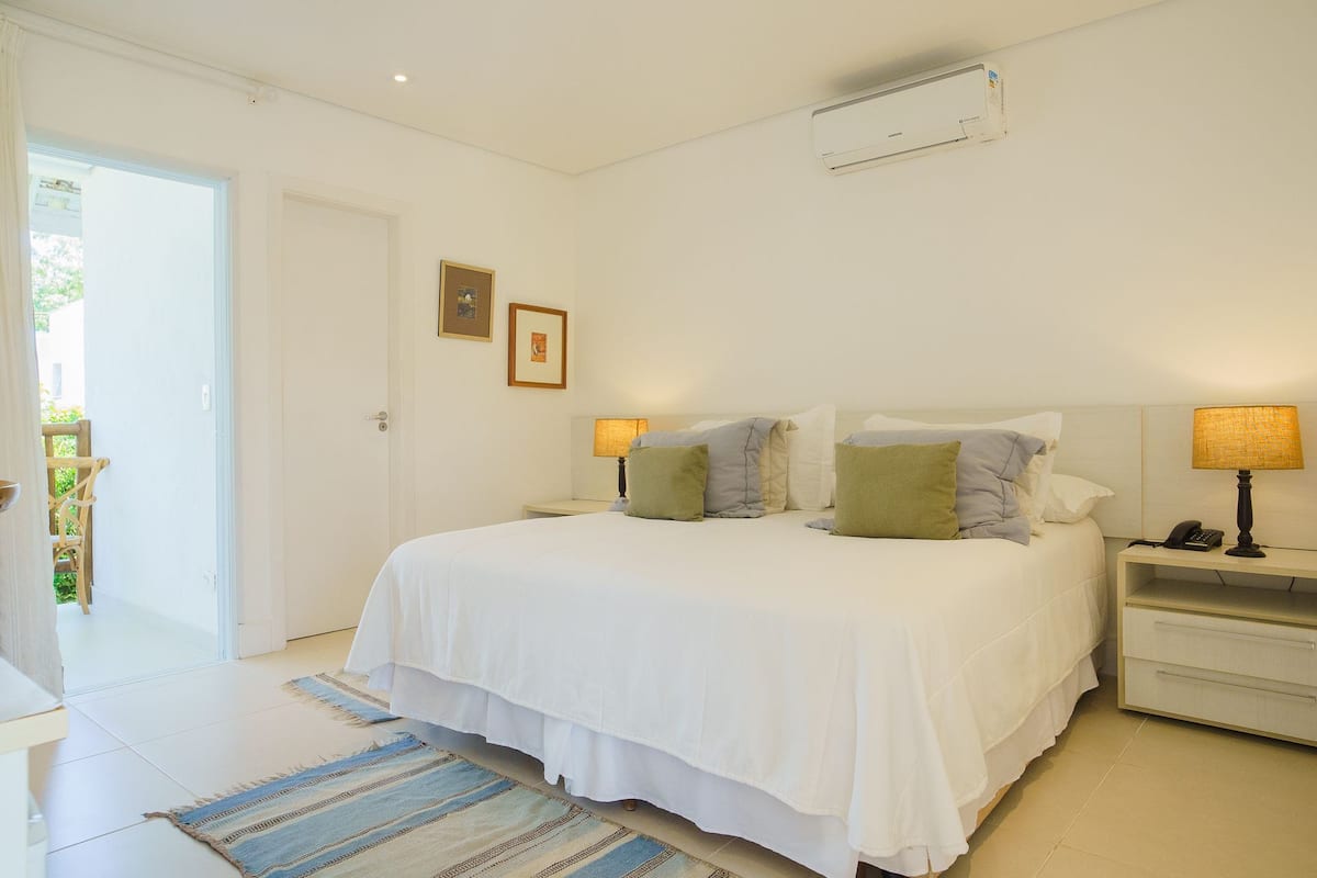 A bedroom with a bed, bedside lamps, a nightstand, and a door leading to a balcony.