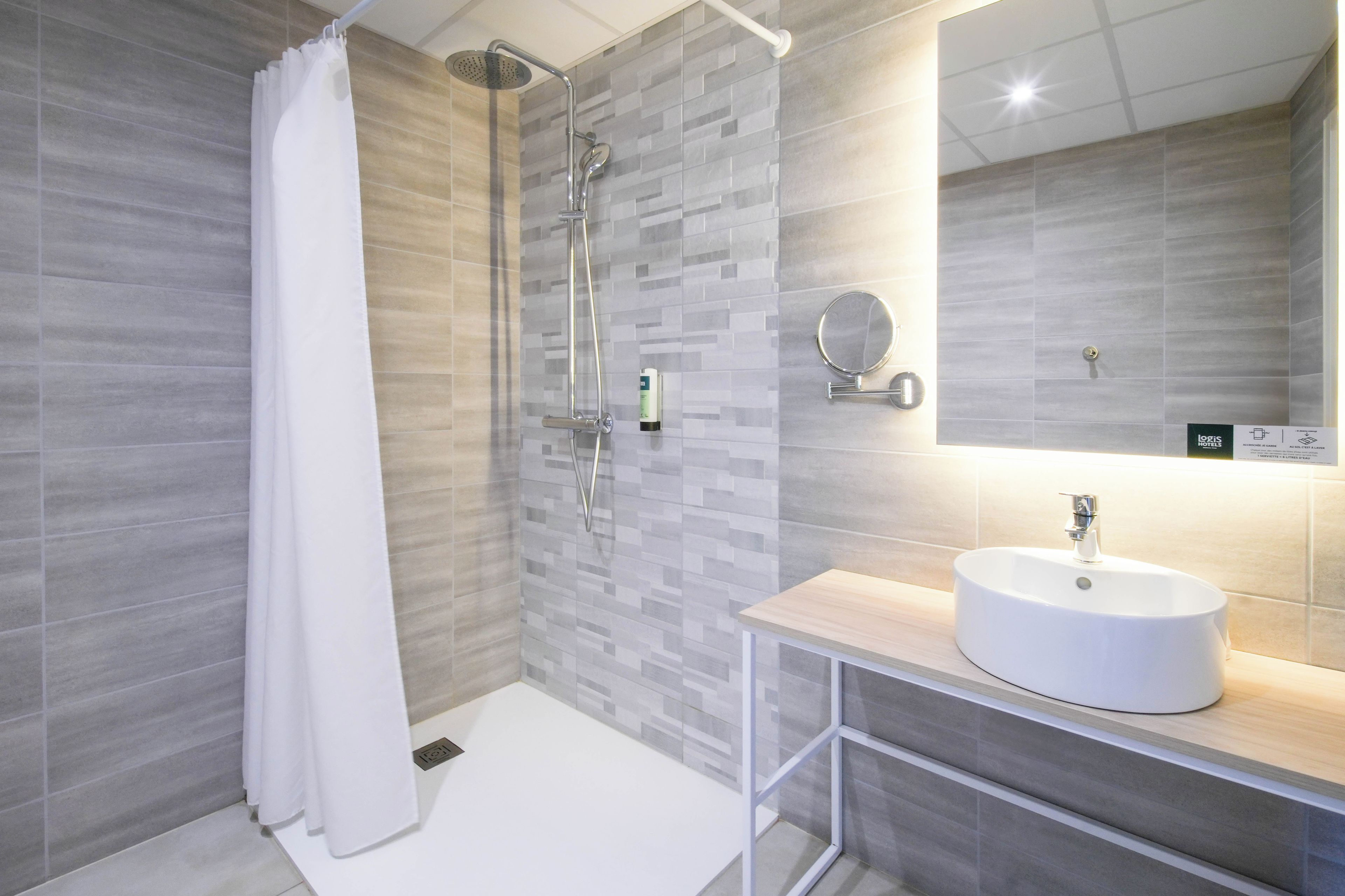 A modern bathroom with a shower, a sink, and a mirror.