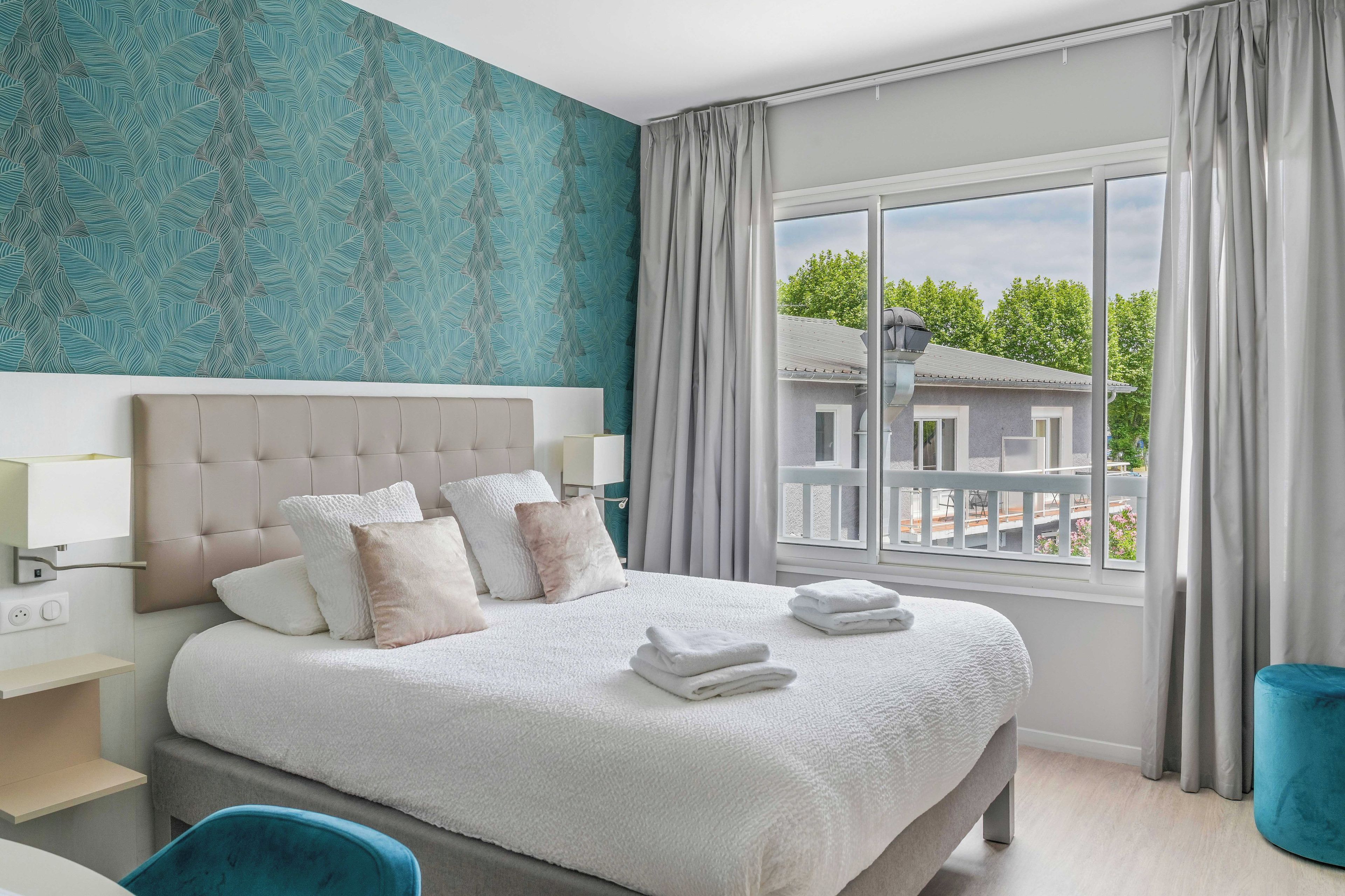 Un dormitorio moderno con una cama grande, vistas a un edificio exterior y una pared con estampado.