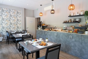 A restaurant with a counter, seating area, and kitchen. - Hôtel l'Amandier (Morlaas)