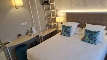 Une chambre d’hôtel comprenant un lit, un bureau avec une lampe, une armoire et une poubelle.