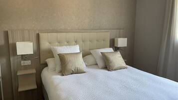 A hotel room with a large bed, two bedside lamps, and a nightstand with a lamp.