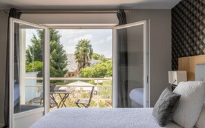 Un dormitorio con un ventanal grande, una cama y vista a un jardín.