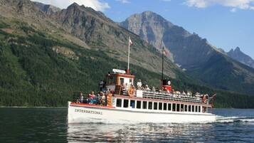 A boat with "INTERNATIONAL" written on the side, passengers on deck, and a mountainous landscape in the background.