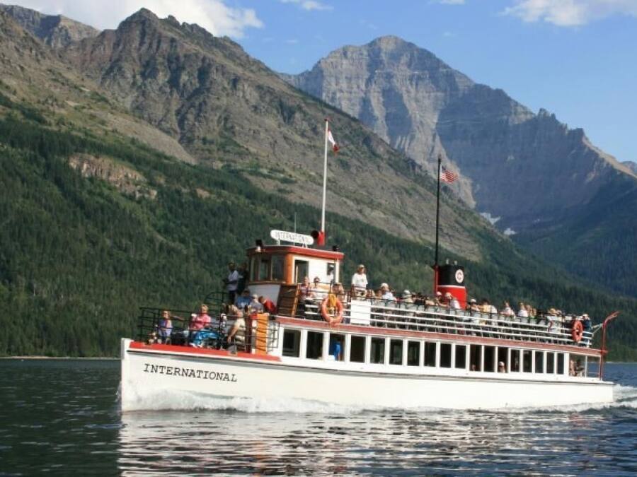 A boat with "INTERNATIONAL" written on the side, passengers on deck, and a mountainous landscape in the background.
