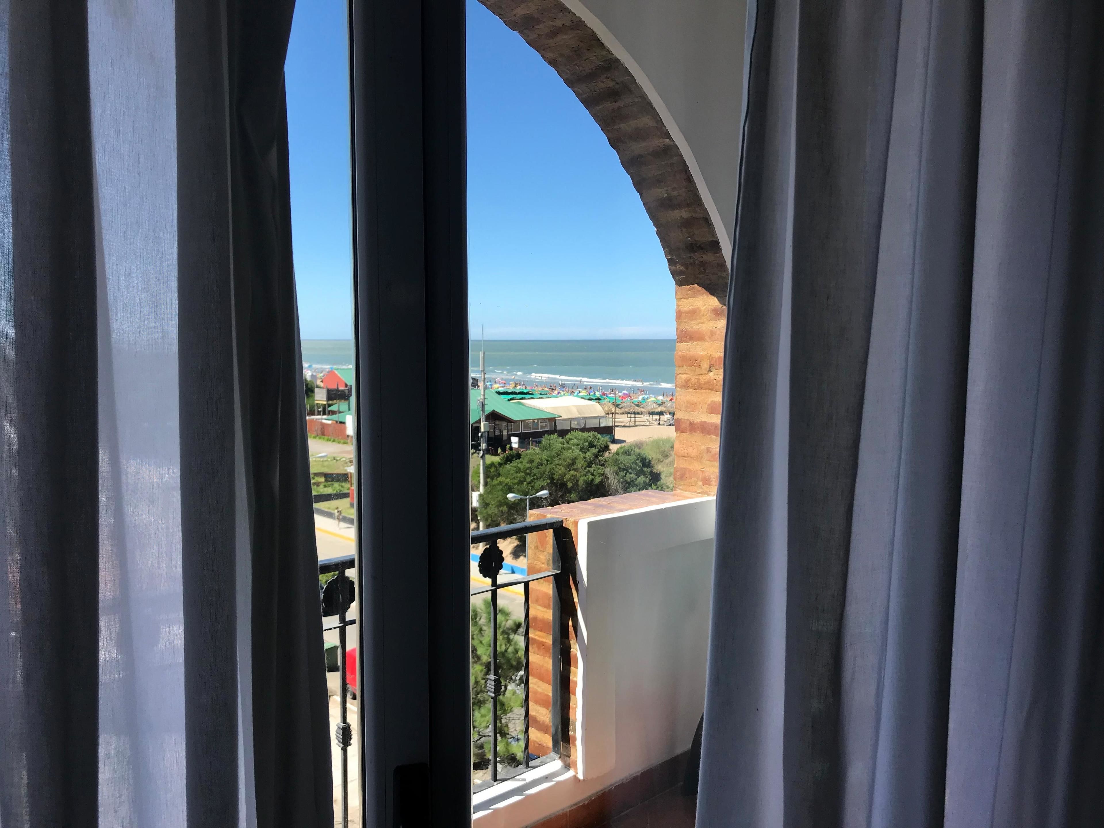 A balcony with a view of the beach and ocean.