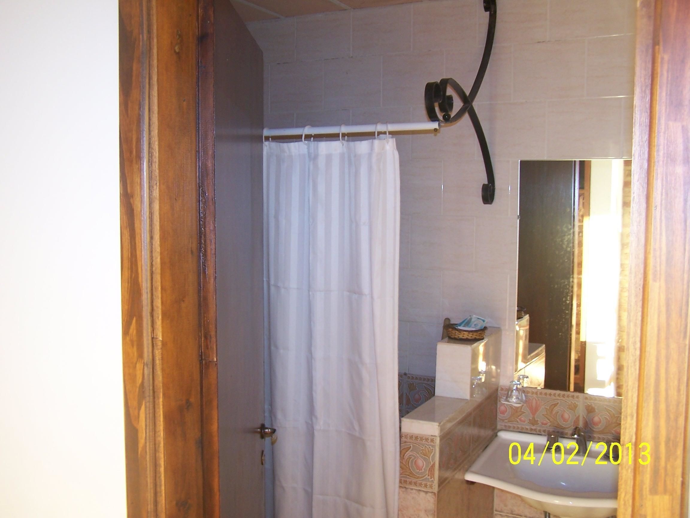 A bathroom with a shower curtain, a sink with decorative tiles, and a mirror.
