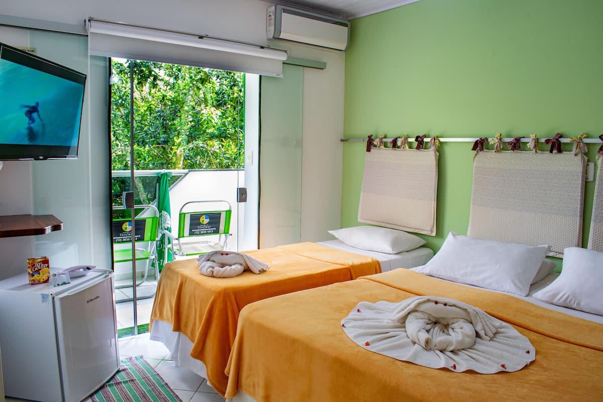 Habitación de hotel con dos camas, televisión, refrigerador y vistas al exterior.