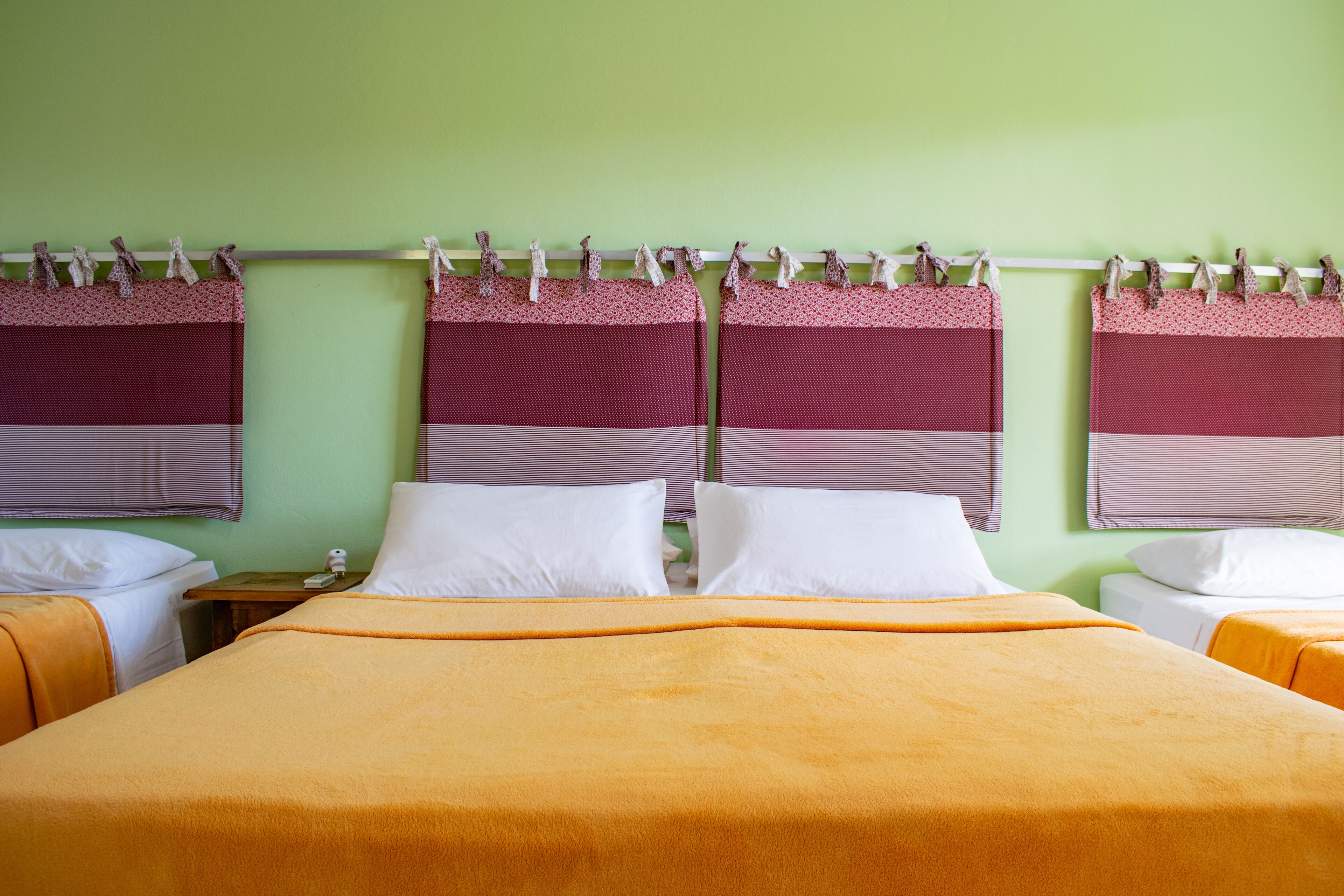 Habitación de hotel con dos camas, cada una con cabeceros rojo y blanco, y una pared verde.