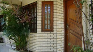 Un edificio con fachada de ladrillo, puerta de madera y ventana con diseño de cuadrícula.