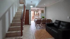 Un amplio espacio habitable con una escalera, un comedor y un sofá de cuero negro.