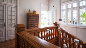 Una escalera con balaustres y barandilla de madera, que conduce a una habitación con paredes blancas y un ventanal grande.