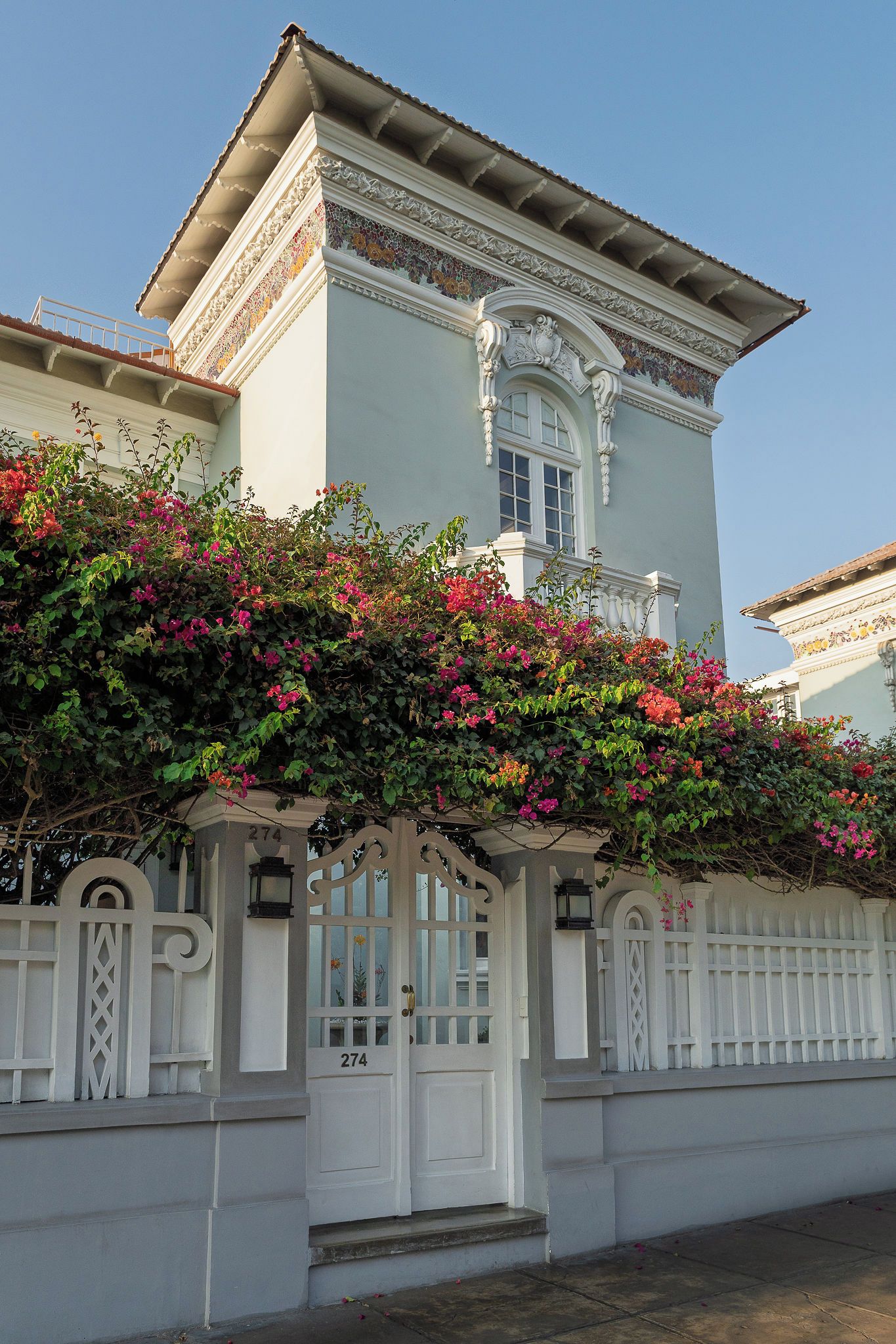 Un edificio con fachada blanca, un acceso decorativo y el número 274 en la puerta.