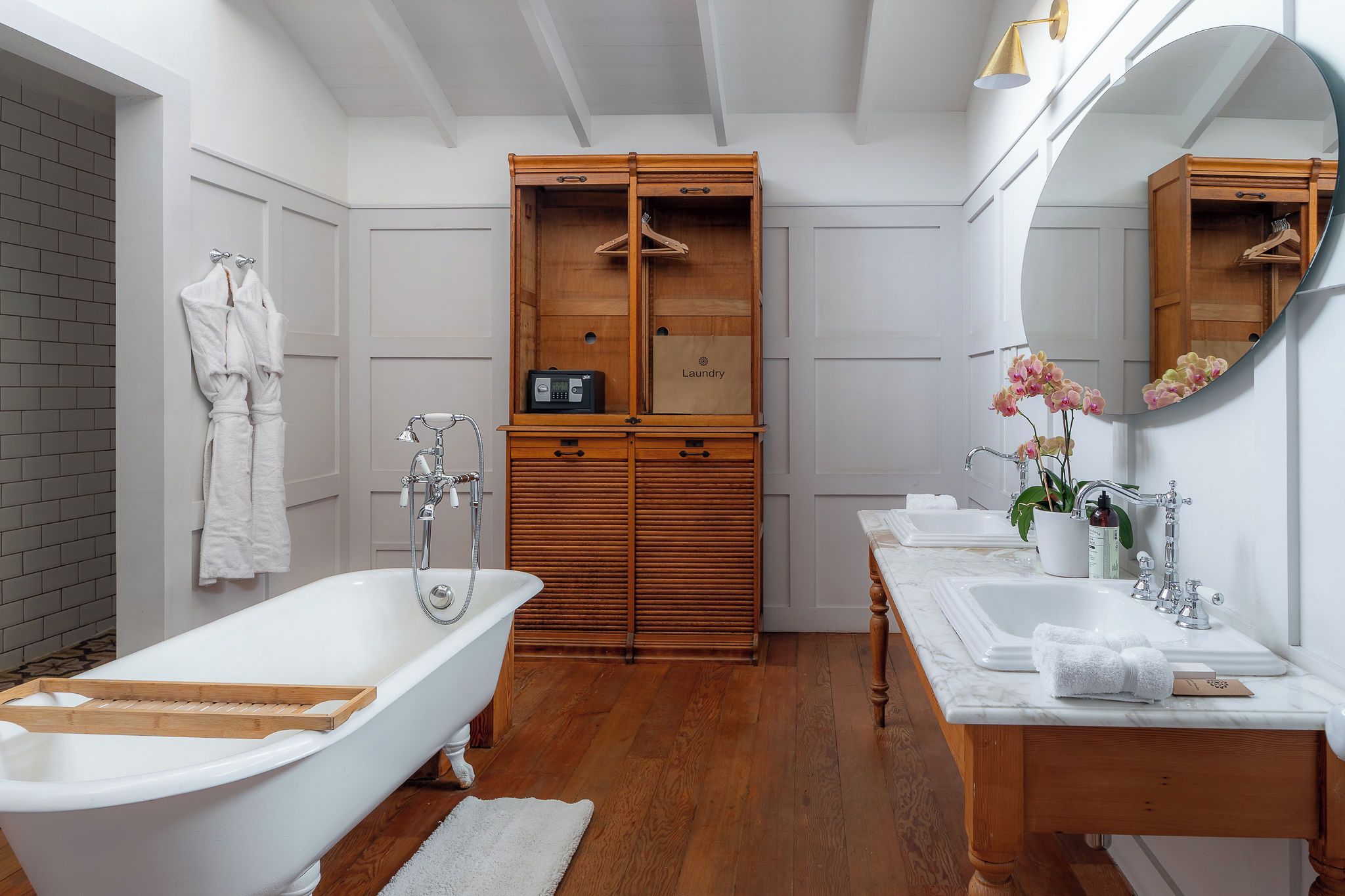 Un baño con una bañera independiente, tocador de madera y un espejo grande.
