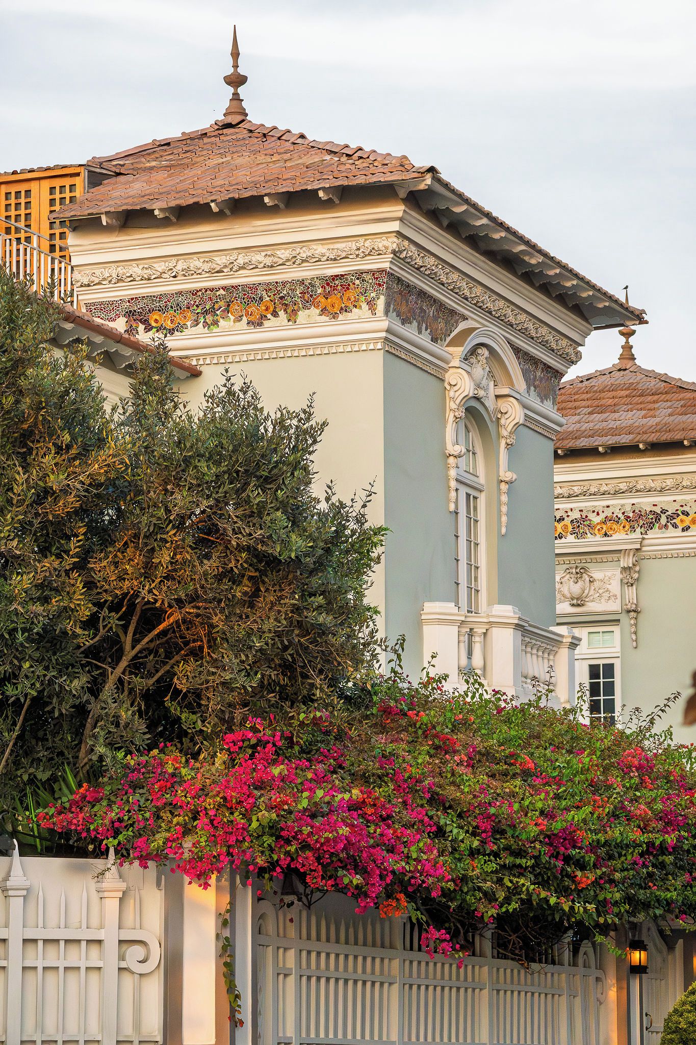 Um edifício com detalhes arquitetônicos elaborados, incluindo telhado em azulejos e molduras decorativas.