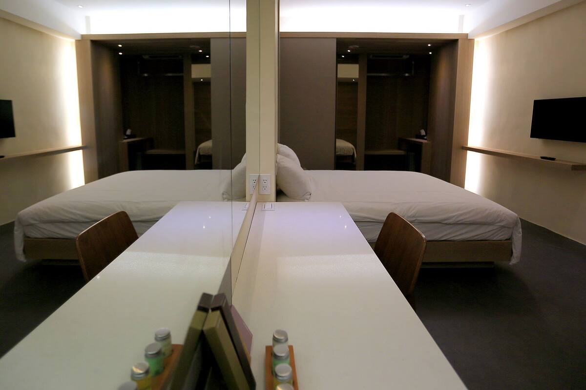 A modern hotel room with a large bed, a desk, and a mirror.