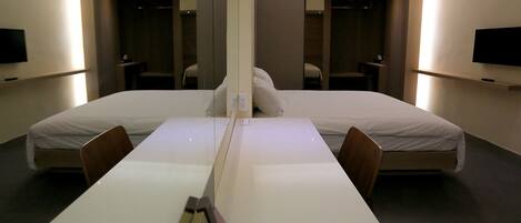 A modern hotel room with a large bed, a desk, and a mirror.