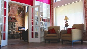 Un salon avec un mur en briques, une bibliothèque, deux fauteuils et un téléviseur.