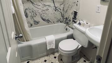 A bathroom with a bathtub, toilet, sink, and a mirror.